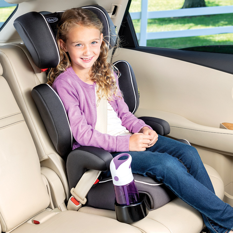 Petite fille souriante et assise dans le siège-auto Graco Assure, avec une bouteille d'eau dans le porte-gobelet