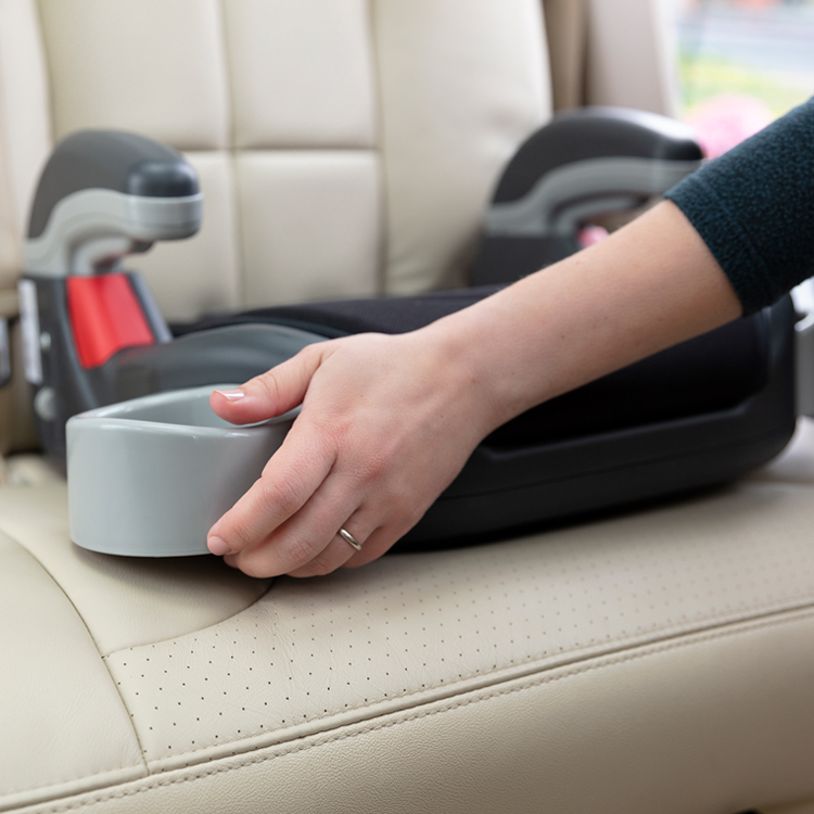 Une personne ouvrant le porte-gobelet rétractable du siège auto Graco Booster Basic.