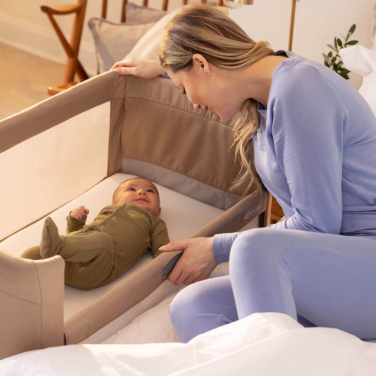 Mama senkt das Seitenteil des Graco® Sweet2Sleep™, um ihr Baby einfacher herausheben zu können.
