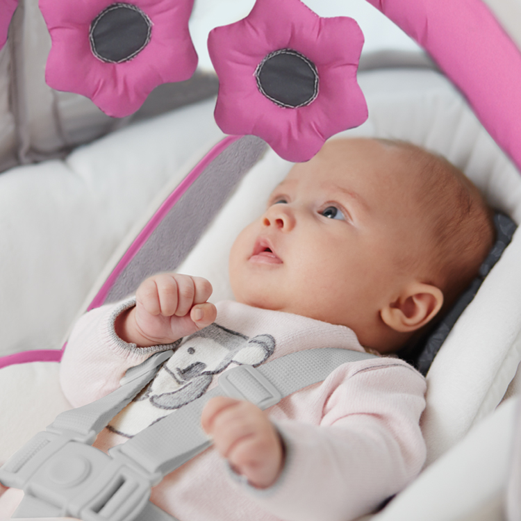 Baby schaut sich die weichen Spielzeuge an der Babyschaukel Graco Glider Elite an