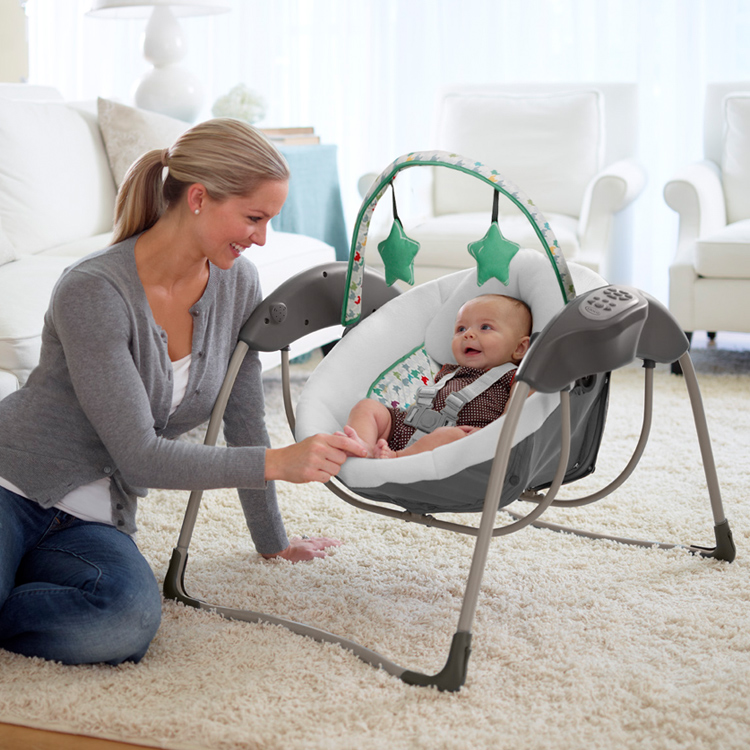 Une femme jouant avec un bébé dans la balancelle Graco Glider Lite
