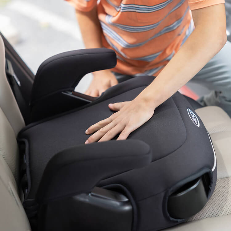 Young boy placing his hand on the soft premium padded seat of Graco Booster Deluxe R129 backless booster. 
