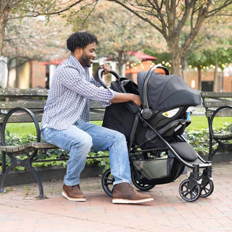 Padre en el parque con su bebé en Graco EeZefold con silla portabebés.