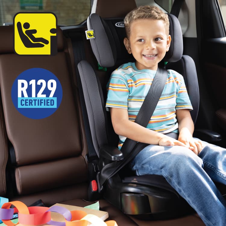 Boy sitting in Graco Junior Maxi i-Size R129 highback booster with i-Size and R129 logos.