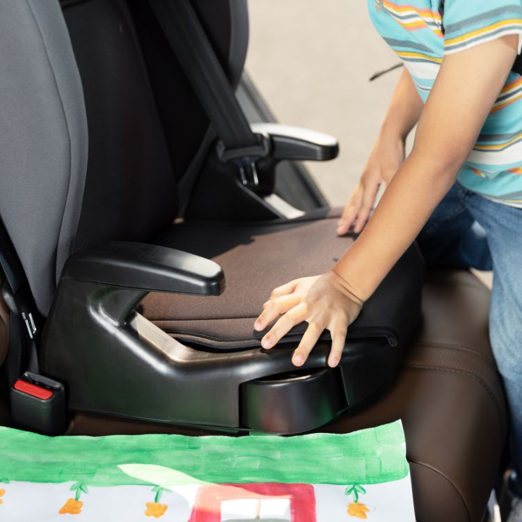 Bambino che mette la mano sulla seduta imbottita del seggiolino auto Junior Maxi i-Size R129 Graco.
