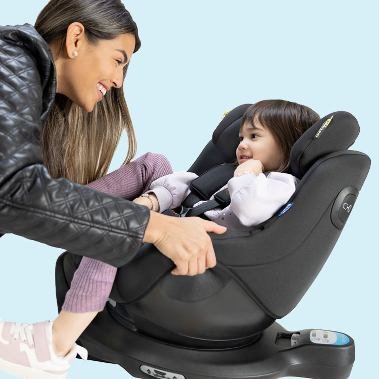 Mum smiling and turning little girl buckled in Graco SnugGo i-Size R129 and connected to the SnugTurn i-Size R129 rotating ISOFIX base
