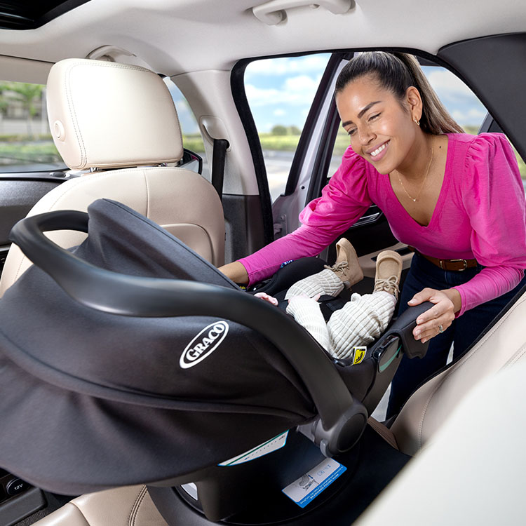 Mom turning SnugLite i-Size R129 infant car seat towards her as it is connected to SnugTurn i-Size R129 rotating ISOFIX car seat base