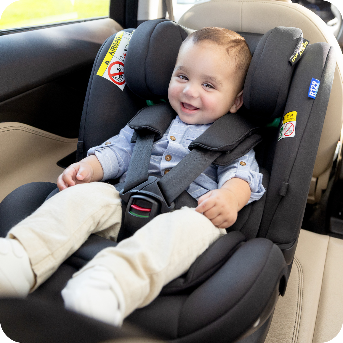 Kid sitting in Graco Logico L highback booster in car with dad standing next to him.
