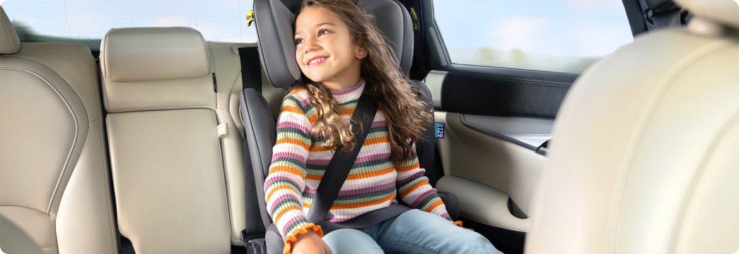 Girl smiling while buckled into Affix i-Size R129 ISOFIX highback booster car seat